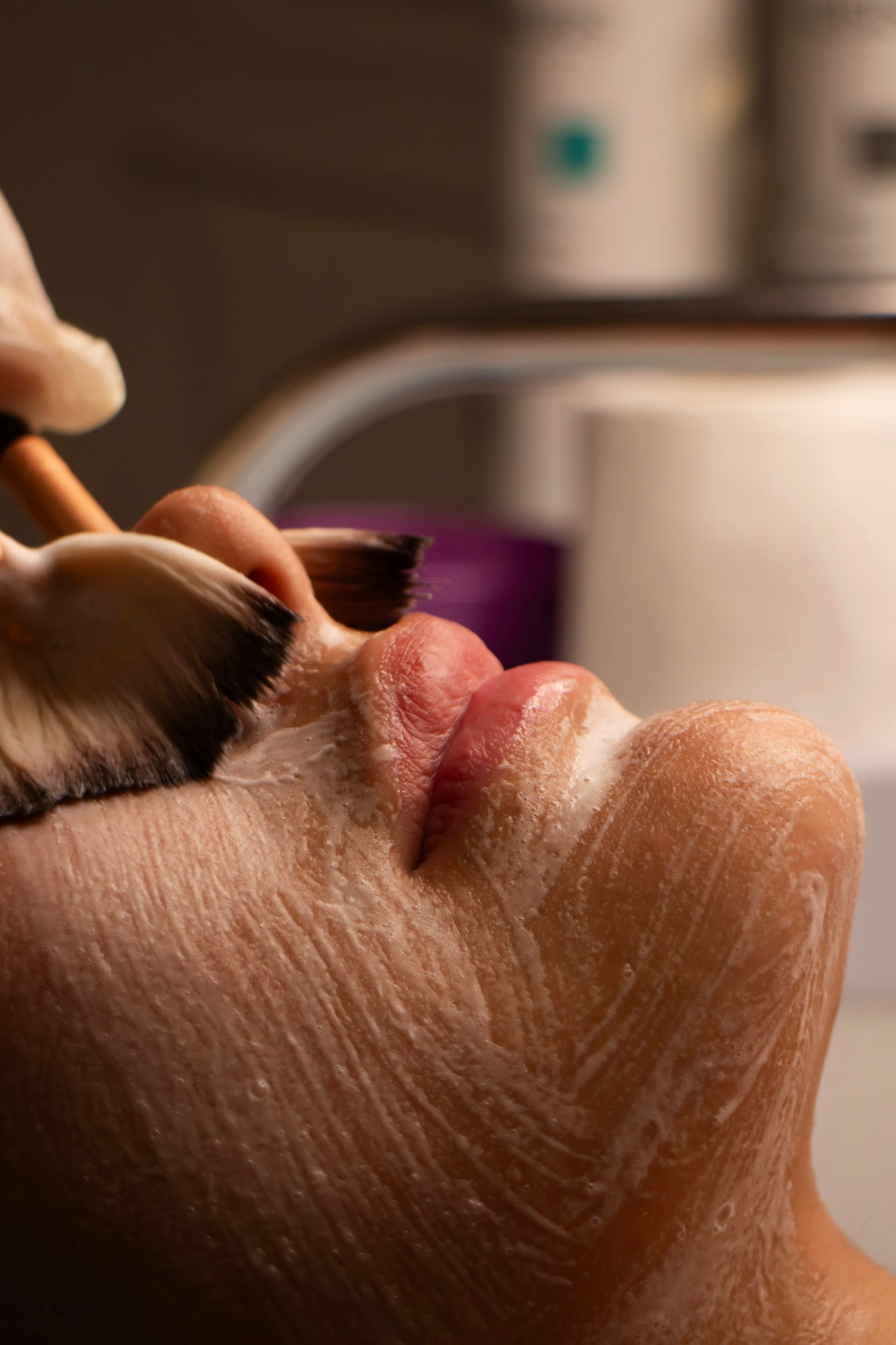 Aplicación de crema blanca con brocha sobre el rostro