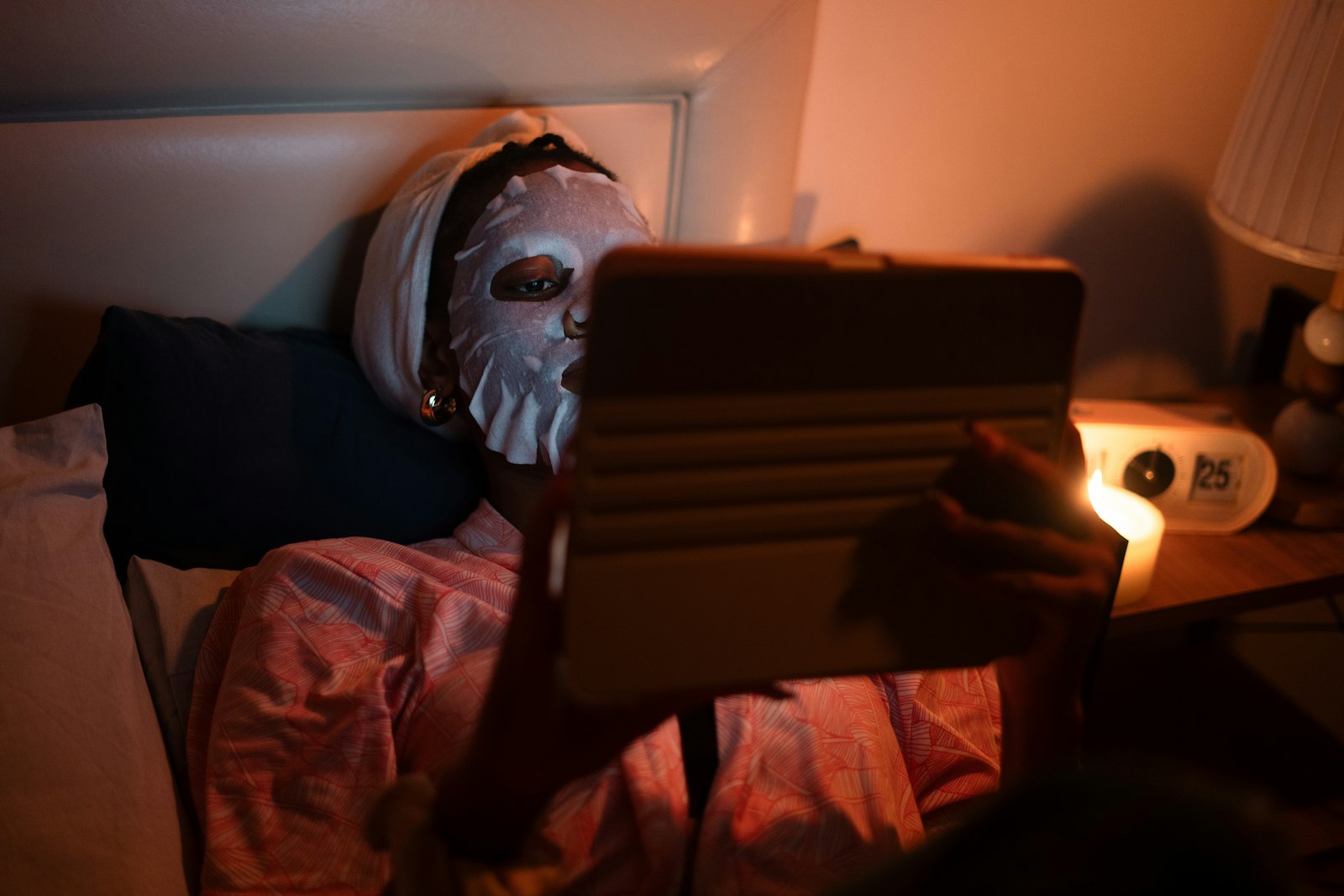 Mujer en la cama usando su rutina de cuidado facial por la noche